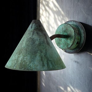 May include: A green metal wall sconce with a cone-shaped shade. The sconce has a weathered, aged look.
