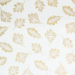Puede incluir: Tela blanca con un patrón repetido de hojas de roble doradas. Las hojas, con vetas detalladas, están dispersas por la superficie. Ideal para manualidades y decoración del hogar con temática otoñal.