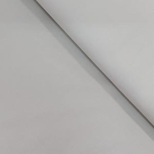 May include: A close-up of a folded, light gray fabric with a subtle textured pattern. The fabric is angled diagonally across the frame, with a rolled edge visible on the right side. The overall appearance is smooth and neutral.
