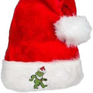 May include: A red Santa hat with a white fluffy trim and a white pom-pom. The hat features an embroidered image of a green cartoon character wearing a Santa hat. This festive hat is perfect for Christmas.