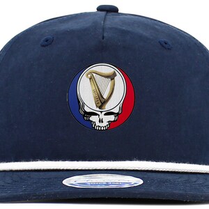 May include: Navy blue cap with a white rope brim. The cap features a circular emblem with a skull, a harp, and the text "EST. 1759" inside a circle with red, white, and blue segments. A stylish accessory.