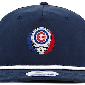May include: Navy blue baseball cap featuring a white rope detail and a circular emblem. The emblem combines the Chicago Cubs logo with a skull design. The cap has a curved brim and a button on top.