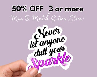 May include: A pink and white sticker with the text "Never let anyone dull your Sparkle" in black lettering. The sticker is being held by a hand.
