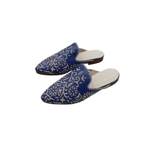 Puede incluir: Un par de zapatillas de cuero azul con un diseño floral blanco. Las zapatillas tienen una punta puntiaguda y un diseño sin cordones. El interior es blanco y la suela es marrón.