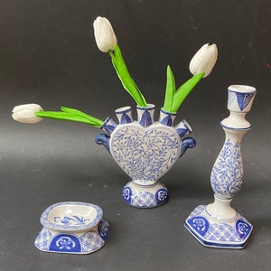 May include: A set of three blue and white ceramic vases with a floral design. The vases are in the shape of a heart, a candlestick, and a small dish. The vases are decorated with a blue and white floral pattern.