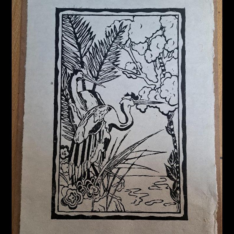 Gravure sur linoléum en noir et blanc représentant deux oiseaux dans un marais. Les oiseaux sont stylisés et ont un long cou et un long bec. L'arrière-plan présente des plantes et de l'eau stylisées.