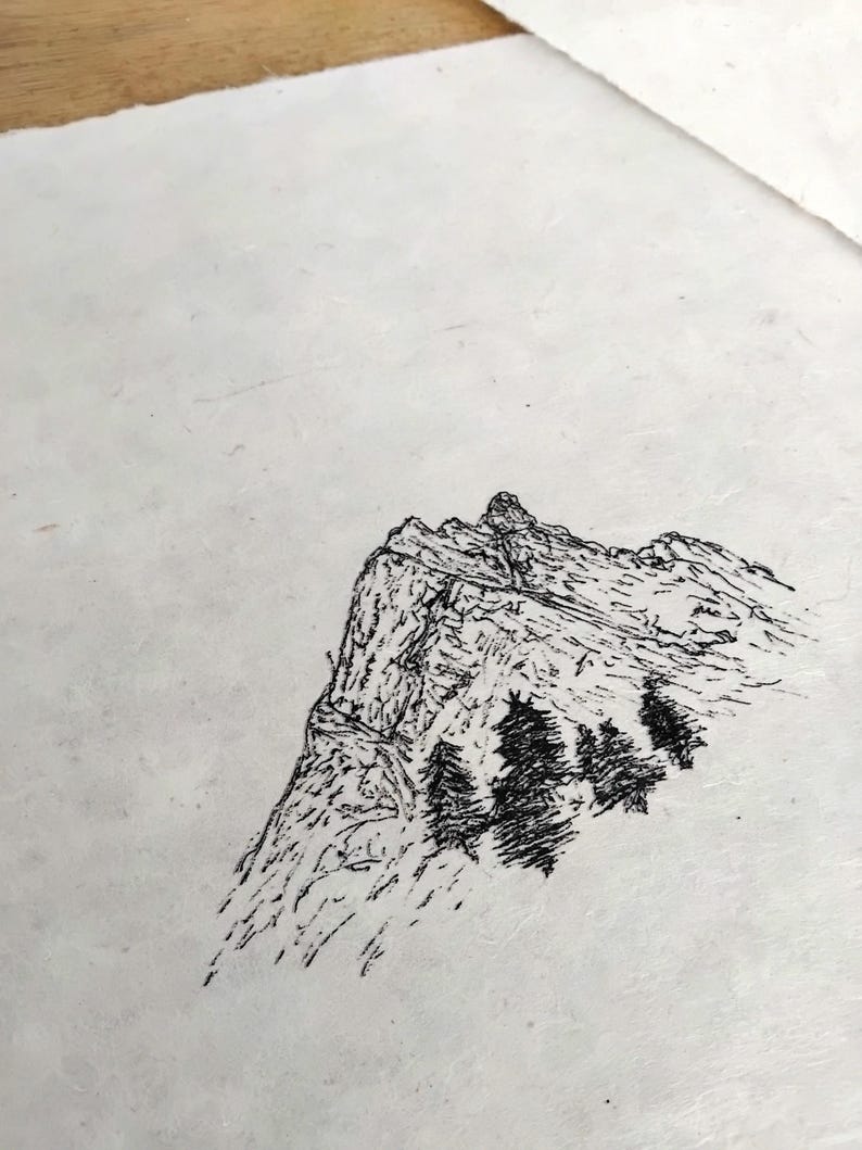 Puede incluir: Dibujo a pluma en blanco y negro de una cordillera con algunos &aacute;rboles. La obra de arte est&aacute; realizada sobre un papel texturizado blanquecino. La monta&ntilde;a tiene un pico irregular y sombreado detallado.