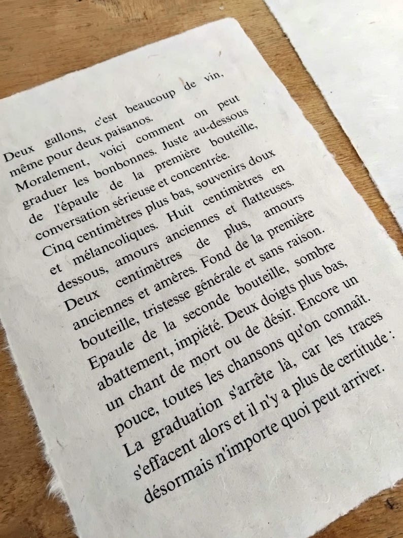 Puede incluir: Primer plano de un papel texturizado blanquecino con texto en franc&eacute;s impreso en tinta negra. El papel tiene un borde &aacute;spero e irregular. El texto parece ser un poema o un pasaje de un libro.