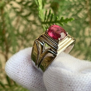 May include: A silver ring with a pink oval gemstone set in a raised, textured setting.