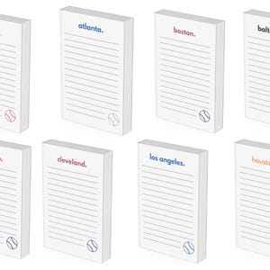 May include: White notepads with lined pages and baseball graphics. Each notepad features a different city name in a colored font: Arizona, Atlanta, Boston, Baltimore, Chicago, Cleveland, Los Angeles, and Houston.