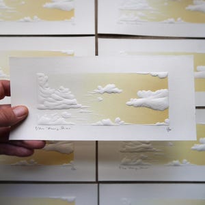Peut inclure: Une impression d'art rectangulaire présentant un ciel en dégradé jaune avec des nuages blancs en relief. L'impression est intitulée "Honey Skies" dans le coin inférieur gauche, avec un numéro d'édition manuscrit et une signature en bas à droite.