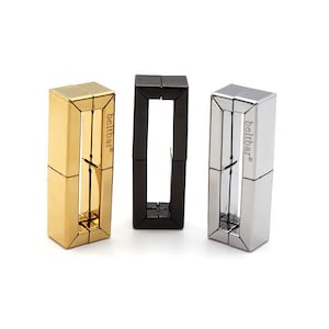 May include: Three metal belt buckle designs in gold, black, and silver. Each buckle features a rectangular shape with a square opening in the centre. The buckles are labelled "beltbar" on the side.