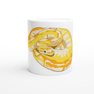 May include: A white ceramic mug with a yellow and white snake illustration. The snake is curled up in a circle with its head facing the viewer.