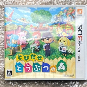 Op de afbeelding: Een Nintendo 3DS-spelcartridge voor Animal Crossing: New Leaf. De hoes heeft een kleurrijk cartoonbeeld van een dorp met verschillende dierenpersonages. De titel van het spel is in het Japans geschreven.
