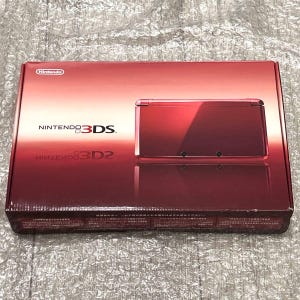Peut inclure: Une console de jeu Nintendo 3DS rouge dans son emballage d'origine. La boîte présente le logo Nintendo et les mots "NINTENDO 3DS" en blanc. La console elle-même est de couleur rouge vif, avec une finition brillante. La boîte est scellée.