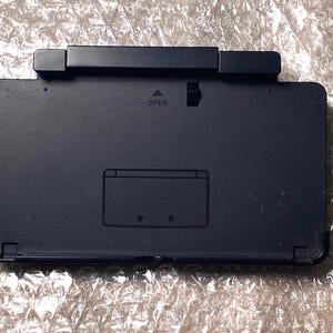 May include: Black Nintendo 3DS XL console with a game card slot and the word "OPEN" printed on the top.