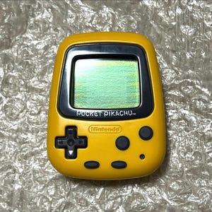 May include: A yellow handheld electronic game with a black screen and buttons. The game is labeled "Pocket Pikachu" and "Nintendo".