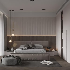 Op de afbeelding: Een moderne slaapkamer met een neutraal kleurenpalet. Het middelpunt is een groot bed met een grijs hoofdbord en beddengoed. Decoratieve hanglampen hangen boven de nachtkastjes. Een poef met patroon en een vloerkleed staan op de voorgrond.