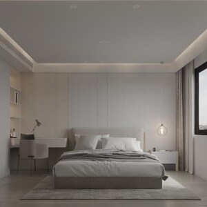Op de afbeelding: Een witte slaapkamer met een groot bed, een bureau en een raam. Het bed heeft een witte hoofdeinde en een grijze deken. Het bureau is wit en heeft een stoel. Het raam is zwart en heeft witte gordijnen.