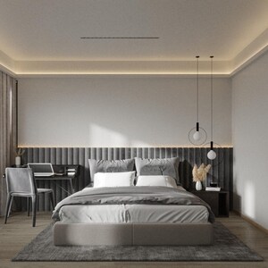 Op de afbeelding: Een moderne slaapkamer met een grijs gestoffeerd bed, een grijs hoofdeinde en een grijs tapijt. Er hangen twee hanglampen aan het plafond en een klein tafeltje met een vaas met gedroogde bloemen staat naast het bed.