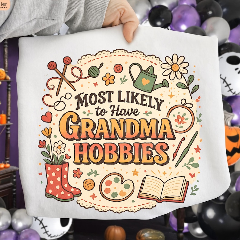 May include: White sweatshirt with the text "MOST LIKELY to Have GRANDMA HOBBIES" in orange and brown. The design includes illustrations of knitting needles, flowers, a watering can, and other craft-related items.
