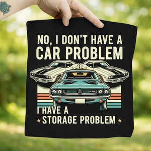 May include: Black tote bag with the text "NO, I DON'T HAVE A CAR PROBLEM I HAVE A STORAGE PROBLEM" and illustrations of classic cars in white and teal. The design includes retro stripes.