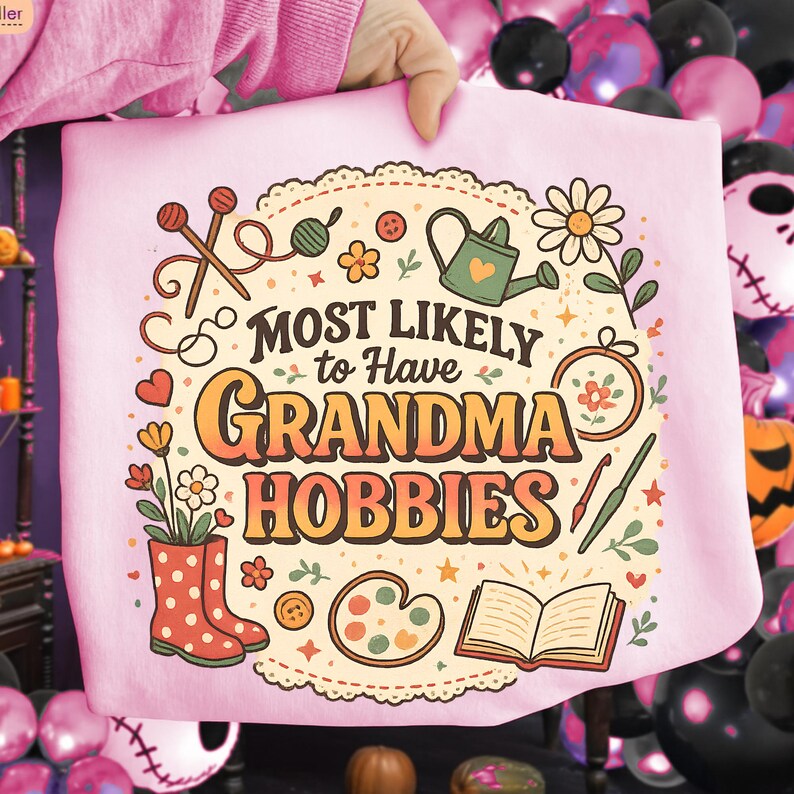May include: A light pink sweatshirt with the text "MOST LIKELY to Have GRANDMA HOBBIES" in orange and brown. The design includes illustrations of knitting needles, flowers, a watering can, and other craft-related items.