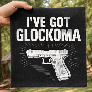 May include: Black graphic tee with the text "I'VE GOT GLOCKOMA" above a white illustration of a handgun. The design includes radiating lines emanating from the gun, creating a bold visual statement.