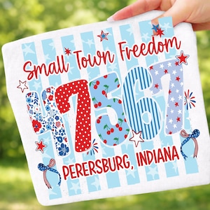 May include: A white rectangular sign featuring the words "Small Town Freedom" in red script. The numbers "47561" are displayed in various patterns, including polka dots, floral, and stripes. The text "PERERSBURG, INDIANA" is at the bottom.