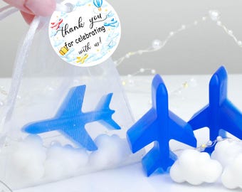May include: Blue airplane-shaped soaps and white cloud-shaped soaps are displayed. One airplane is inside a clear bag with white filler. A round tag reads "Thank you for celebrating with us!" in script.