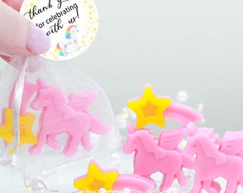 May include: Pink unicorn and yellow star-shaped soap favors. Some are in a clear bag with a tag that says "thank you for celebrating with us!". Handmade soap favors with a Sandra Soap logo.