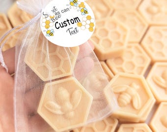 May include: A white sheer organza drawstring bag containing two hexagonal light yellow wax pieces, one with a honeycomb pattern and one with a bee relief. A round tag attached to the bag features bee illustrations and the text Sweet as can Bee Custom Text.