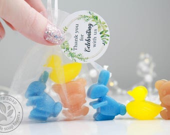 May include: A sheer mesh bag filled with colorful, animal-shaped soaps. The soaps include blue bunnies, yellow ducks, and a brown bear. A round tag reads "Thank you for Celebrating with us."