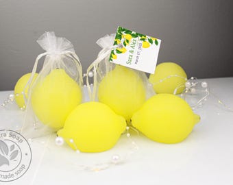 May include: Bright yellow lemon-shaped soaps packaged in sheer white organza drawstring bags. One bag features a rectangular tag with a lemon illustration and the printed text Sara & Alex March 17, 2025. A string of small white faux pearls is draped around the soaps.