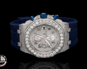 May include: A silver wristwatch with a blue rubber band and a diamond-encrusted bezel. The watch face is white with silver hands and markers. The watch has a chronograph function.