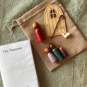 Peut inclure: Un ensemble de jeu sur le thème de la Pâque, comprenant une petite porte en bois, une canne de berger, une figurine de mouton et plusieurs poupées en bois. L'ensemble comprend un sac à cordon et un livret intitulé "La Pâque" avec Exode 12:1-42.