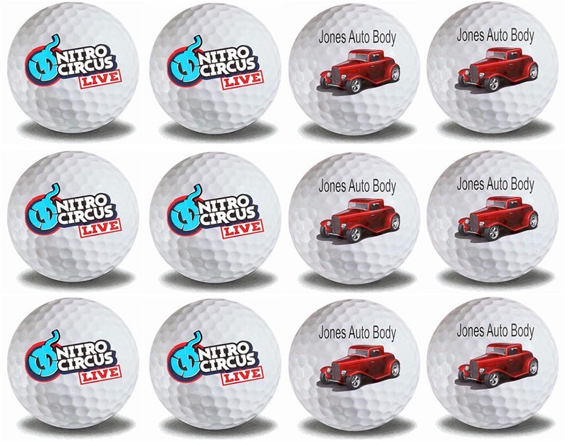 May include: Twelve white golf balls with different designs. Six balls feature a blue and red logo that says "Nitro Circus Live". Six balls feature a red hot rod car with the text "Jones Auto Body".