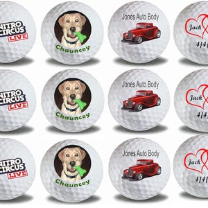 May include: Nine white golf balls with different designs. Three golf balls feature a logo for Nitro Circus Live. Three golf balls feature a dog with the name Chauncey. Three golf balls feature a red car with the text Jones Auto Body and a heart design with the text Jack Diane and the date 4/4/20.
