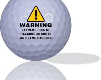 May include: A white golf ball with a yellow warning sign and black text that reads "WARNING EXTREME RISK OF HAZARDOUS SHOTS AND LAME EXCUSES".