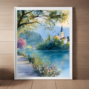 Könnte beinhalten: Ein gerahmtes Landschaftsgemälde zeigt eine ruhige Seeszene mit einer Kirche auf einer Insel. Das Kunstwerk zeigt einen Weg am Ufer, üppiges Grün und einen Baum mit gelben und grünen Blättern. Der Himmel ist ein sanftes Blau.