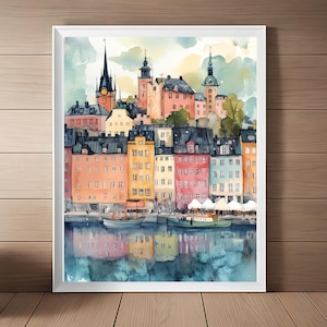 Könnte beinhalten: Aquarellmalerei einer farbenfrohen Stadtlandschaft mit Gebäuden, die eine Uferpromenade säumen. Die Gebäude sind in Rosatönen, Gelb, Blau und Grün gemalt. Das Wasser spiegelt die Gebäude und den Himmel wider, der hellblau mit weißen Wolken ist.