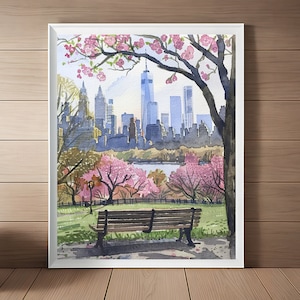 Op de afbeelding: Een aquarel schilderij van een park scène in New York City. Een houten bankje staat op de voorgrond, met uitzicht op de skyline van de stad, inclusief de Freedom Tower. De bomen in het park bloeien met roze bloemen.