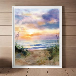 Könnte beinhalten: Aquarellmalerei einer Strandszene bei Sonnenuntergang. Ein sandiger Pfad führt zum Meer, flankiert von hohen Gräsern und Pflanzen. Der Himmel ist eine Mischung aus Orange, Gelb, Blau und Lila und schafft eine ruhige Küstenlandschaft.