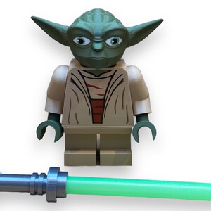 May include: A green and brown Lego minifigure of Yoda from Star Wars, holding a green lightsaber.