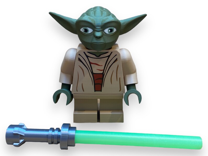 May include: A green and brown Lego minifigure of Yoda from Star Wars, holding a green lightsaber.