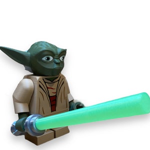 May include: A green Yoda Lego minifigure with a tan robe and a green lightsaber.