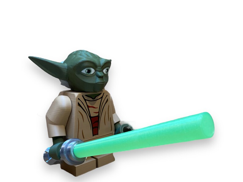 May include: A green Yoda Lego minifigure with a tan robe and a green lightsaber.