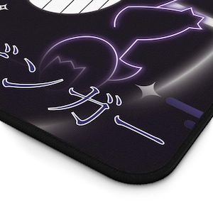 May include: Black mouse mat with a purple and white graphic design. The design features Japanese characters and a stylized image of a creature. The mouse mat has a black border.
