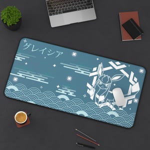 May include: A rectangular mousepad with a blue background featuring a white illustration of a cartoon character and Japanese text. The design includes wave patterns and geometric shapes. A white mouse rests on the pad.
