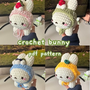 May include: Four crochet bunny figures in white with different colored hats and scarves: pink, green, blue, and yellow. The image includes the text "crochet bunny pdf pattern".